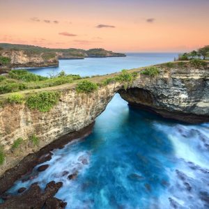 Stone arch over the sea. Broken beach, Uug beach, Nusa Penida, Indonesia. soft tones and warm sunset.